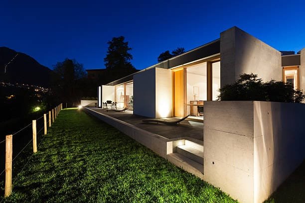 beautiful modern house in cement, view from the garden, night scene