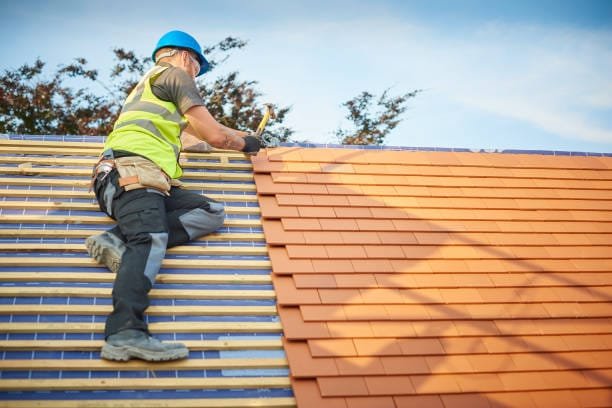 a roofer nails on the roof tiles