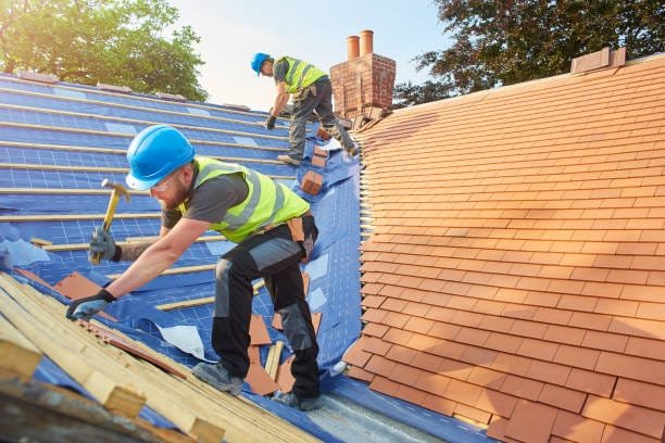 a roofer nails on the roof tiles